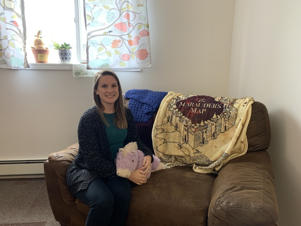 womam on couch with purple stuffed unicorn and Marauders Map blanket